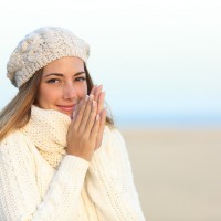 Woman warmly clothed in a cold winter on the beach with the sky in the background